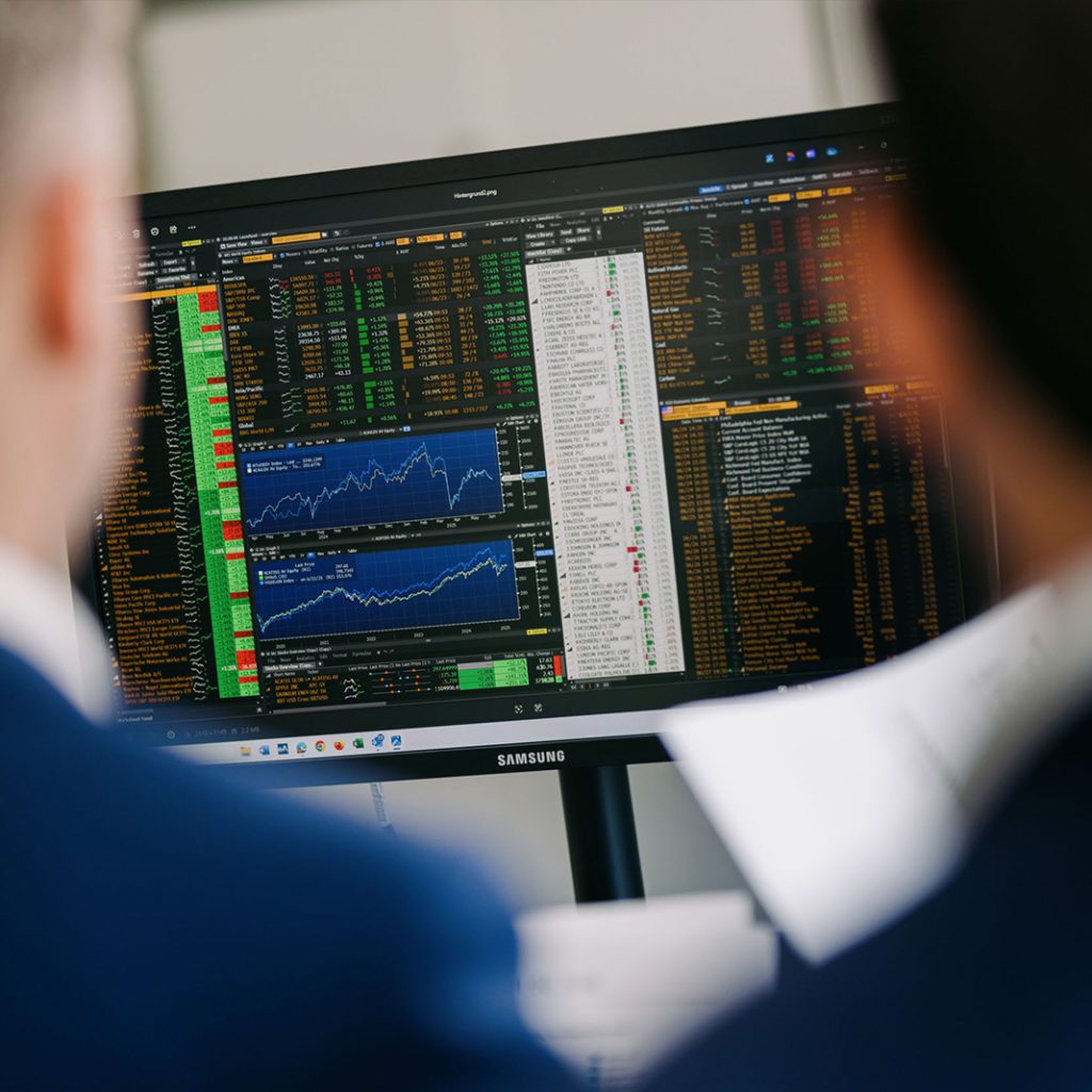 Mitarbeiter von W&L Asset Management betrachten einen Bildschirm mit Aktienkursen für eine kostenlose Portfolio-Analyse