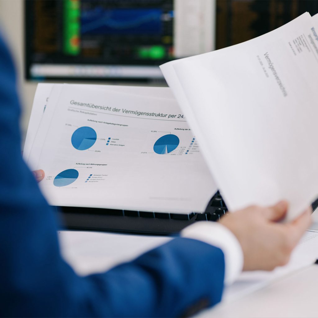 Mitarbeiter von W&L Asset Management hält einen Stapel Dokumente für eine persönliche, kostenlose und unverbindliche Portfolio-Analyse